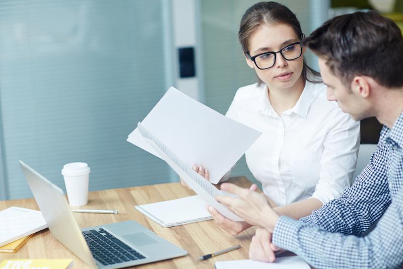 Adviser reviewing official documents with a client in an office, representing administrative support in Spain