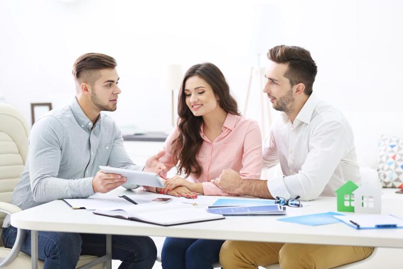 Couple in a meeting with a financial adviser reviewing documents before transferring money to Spain.