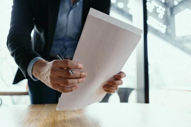 Person reviewing official documents with a pen in hand, relevant to requesting and understanding a nota simple in Spain